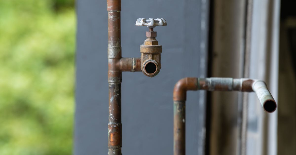 Detailed view of an old, rusty industrial water pipe with valve, conveying vintage industrial aesthetics.