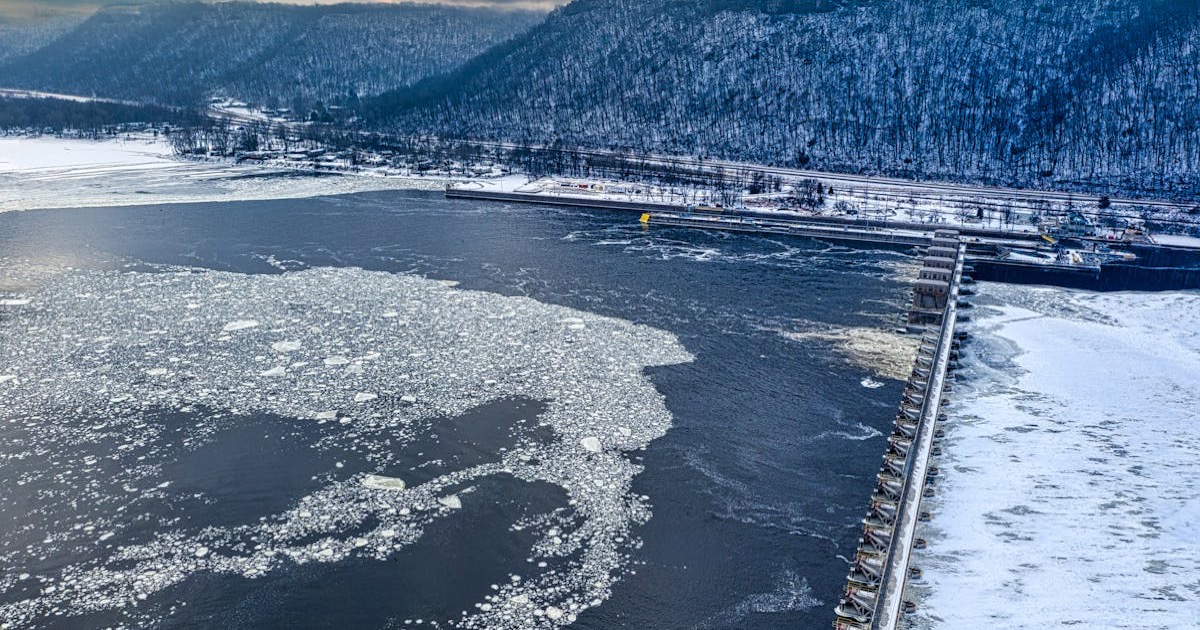 Aerial view of the icy Mississippi River and dam in Minnesota City, showcasing winter's beauty.