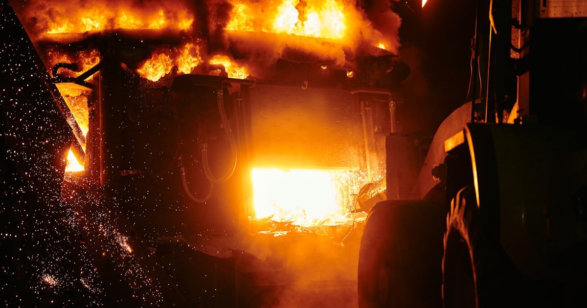 Close-up of a fiery furnace in an industrial setting emitting intense flames and sparks.